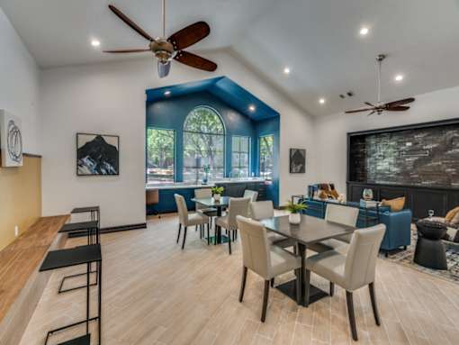 A dining room with a table set for six and a ceiling fan.