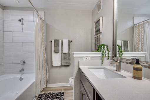 A bathroom with a white tub, sink, and towel rack.