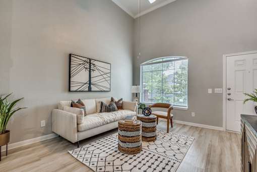 A living room with a white couch, a wooden table, and a large window.