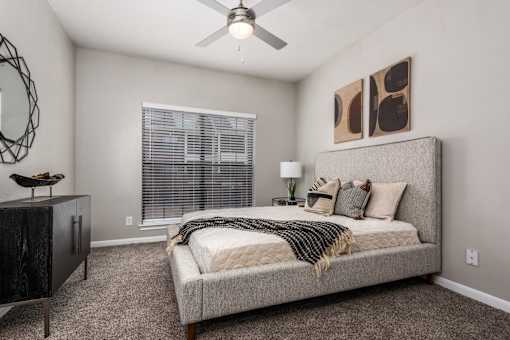 A bedroom with a bed, a dresser, and a ceiling fan.