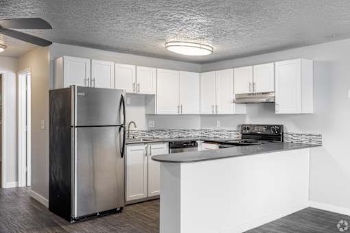 Modern open floorplan kitchen with stainless steel appliances and white cabinets at The Groove apartments in the Hazel Dell 98665 neighborhood in Vancouver, Washington.