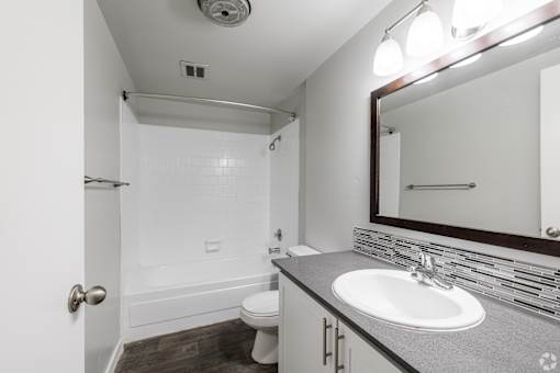 Spacious bathroom with white walls and dark wood-style flooring at The Groove apartments in the Hazel Dell 98665 neighborhood in Vancouver, Washington.