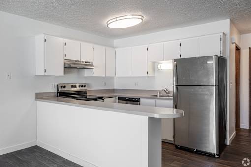 A modern kitchen with white cabinets and stainless steel appliances at The Groove apartments in the Hazel Dell 98665 neighborhood in Vancouver, Washington.