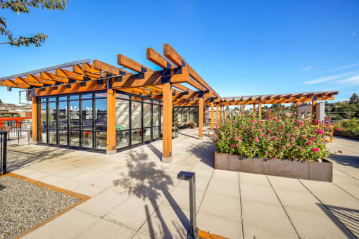 a covered patio with flowers and a glass building with a roofat The Hayes on Stone Way, Seattle