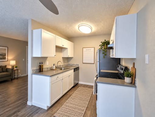 A kitchen with white cabinets and a black refrigerator.