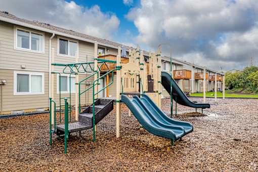 A playground with a green slide and a climbing frame.