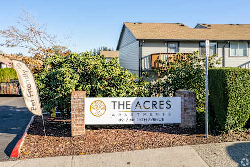 The sign for The Acres apartments is in front of a building.