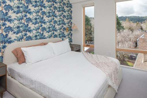 A bedroom with a large bed and a view of the outdoors through a window.