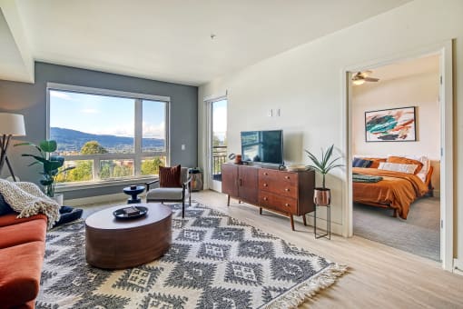 a living room with a tv and a bedroom in the background