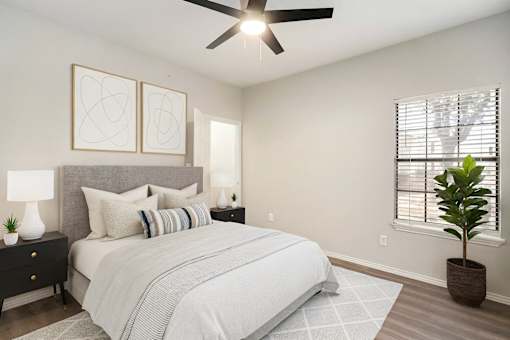 A bedroom with a large bed, a ceiling fan, and two wall lamps.