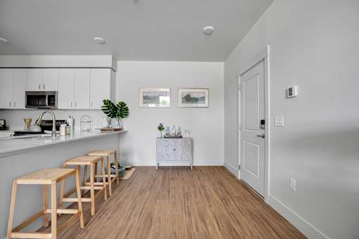 A kitchen with white cabinets and wooden floors.