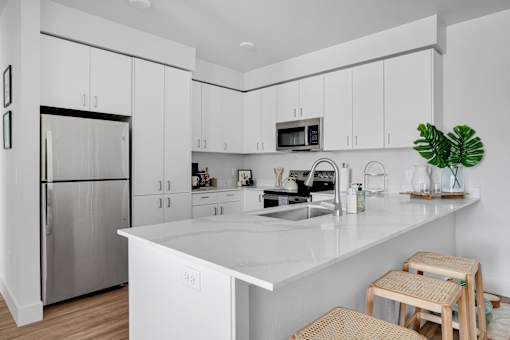 A modern kitchen with white cabinets and a stainless steel refrigerator.