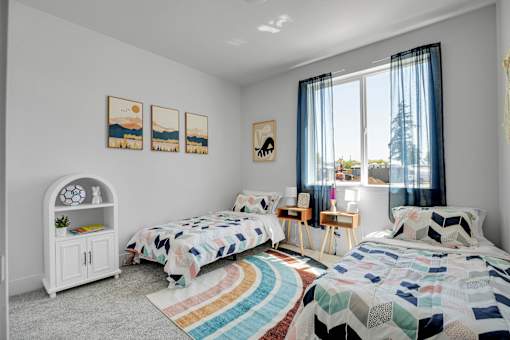 A bedroom with two beds, a dresser, and a bookcase.