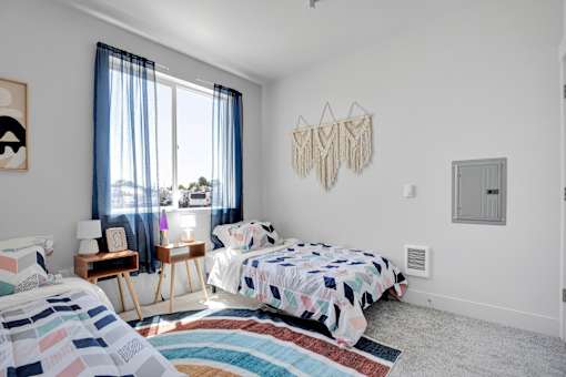 A bedroom with a bed, a chair, and a window with curtains.