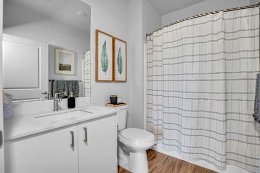 A white bathroom with a toilet, sink, and shower curtain.