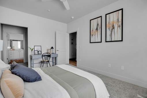 A bedroom with a bed, desk, and two framed pictures on the wall.