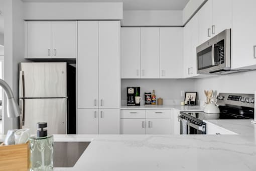 A modern kitchen with white cabinets and appliances.