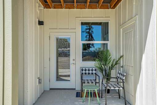 A white door with a window above it and a chair and stool in front of it.