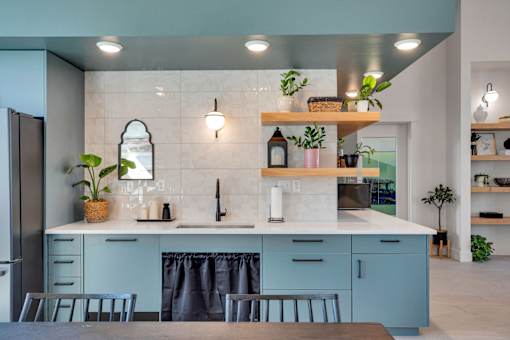 A kitchen with a blue cabinet and a counter with a plant on it.