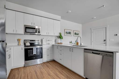A modern kitchen with white cabinets and stainless steel appliances.
