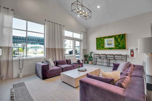 A living room with a purple couch and a large window.