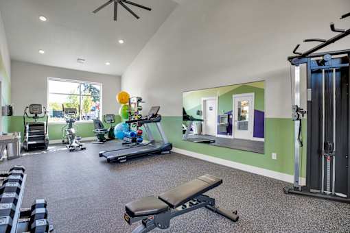 A gym with a variety of equipment including a treadmill, weights, and a bench.