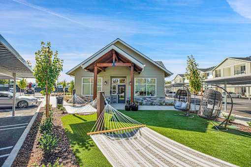 A modern house with a hammock in the front yard.
