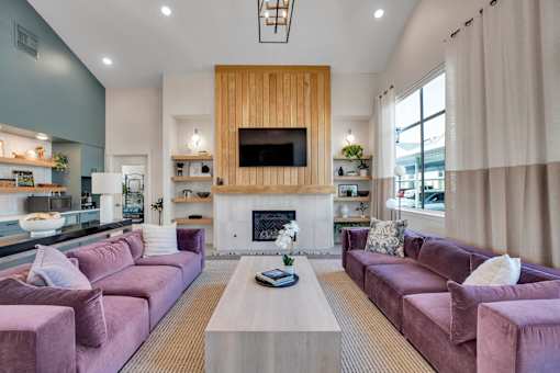 A living room with a fireplace and a television mounted above it.