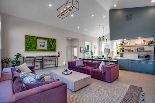 A modern living room with purple couches and a bar area.