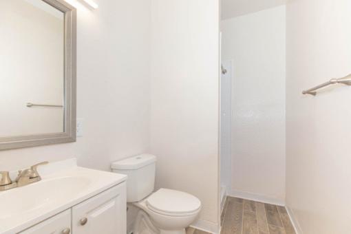 A white bathroom with a toilet, sink, and mirror.