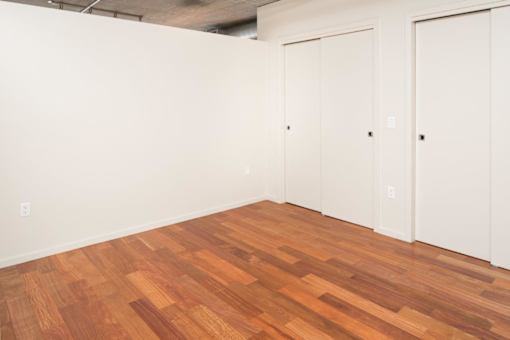 A room with wooden floors and white walls with two doors.