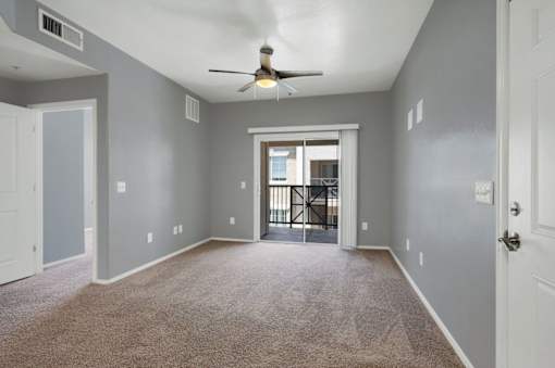 A spacious room with a ceiling fan and carpeted floor.