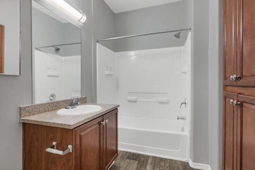 A bathroom with a sink, mirror, and shower.