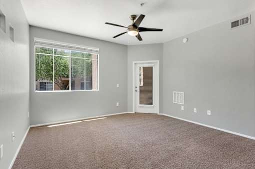 A room with a ceiling fan and carpeted floor.
