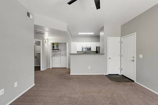 A spacious room with a kitchen area in the background.