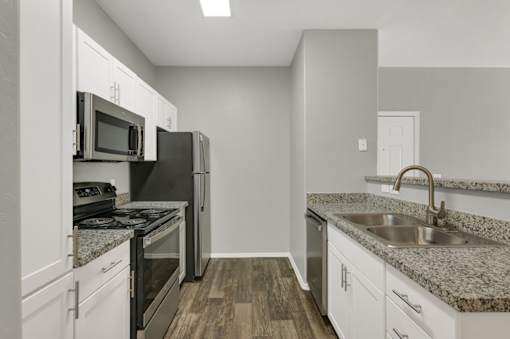 A kitchen with a granite countertop and stainless steel appliances.