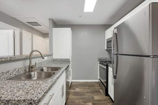 A kitchen with a granite countertop and stainless steel appliances.