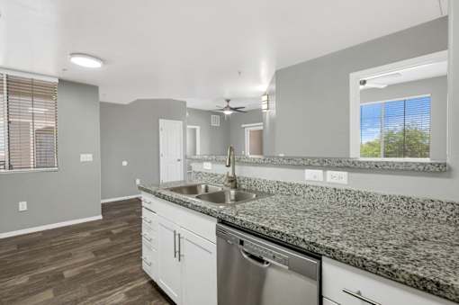 A kitchen with a stainless steel dishwasher and granite countertops.