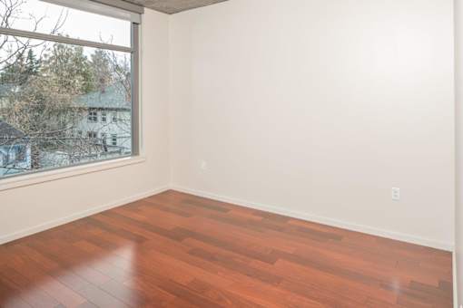 Empty room with wooden flooring and a window.