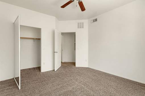 A room with a carpeted floor and a ceiling fan.