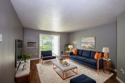a living room with blue couches and chairs and a rug