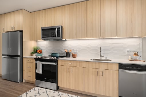 a kitchen with wooden cabinets and stainless steel appliances at The Hemlock, Seattle, WA