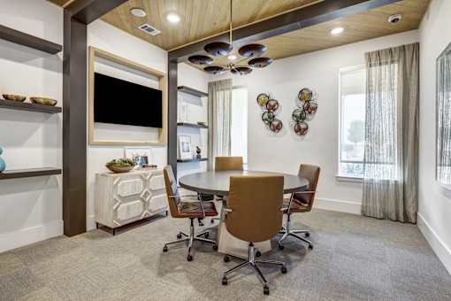 A conference room with a table, chairs, and a TV.