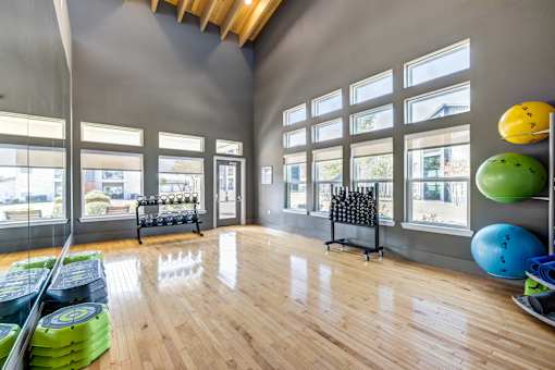 A gym with a wooden floor and a bench outside the window.