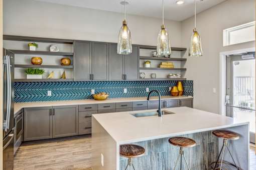 A kitchen with a white counter top and wooden bar stools.