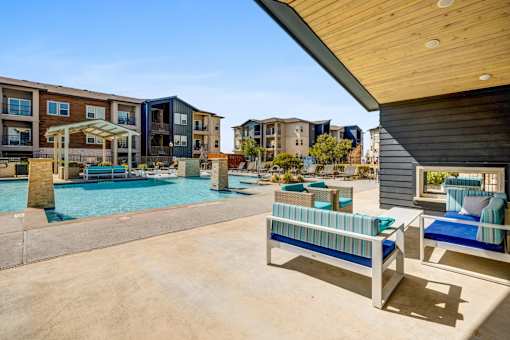 A pool area with a bench and a table in front of apartment buildings.