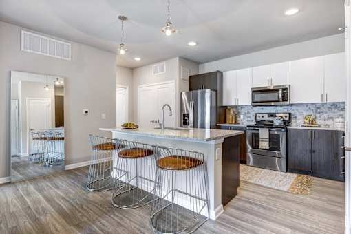 A kitchen with a white island and bar stools.