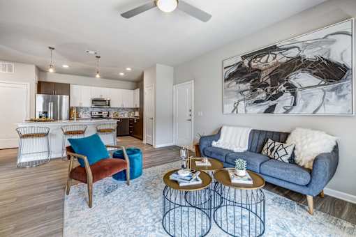 A living room with a blue couch and a large painting on the wall.