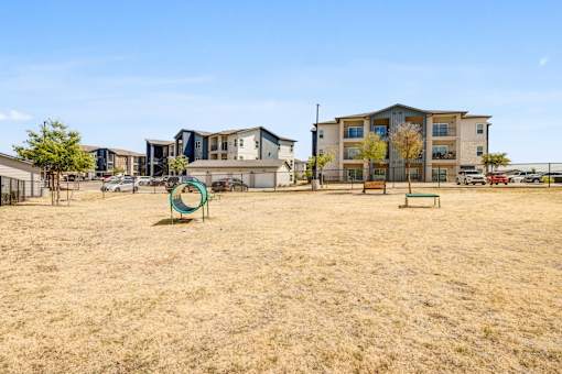 A playground with a green ring and a bench in front of apartment buildings.