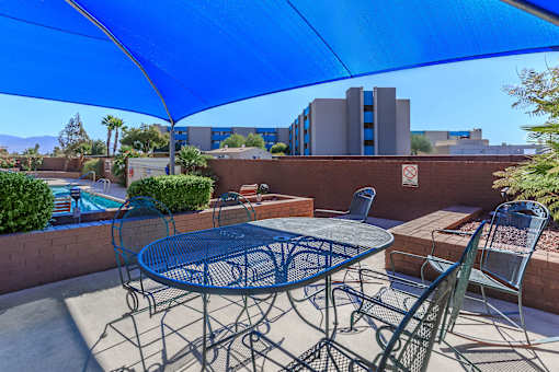 A patio with a table and chairs under a blue umbrella.